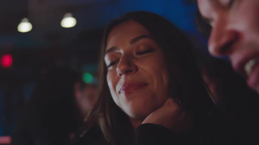 Woman drinking beer in a brightly lit nighttime setting