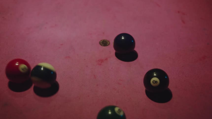 Billiard balls in a triangle on a pink table being scrambled by a white ball