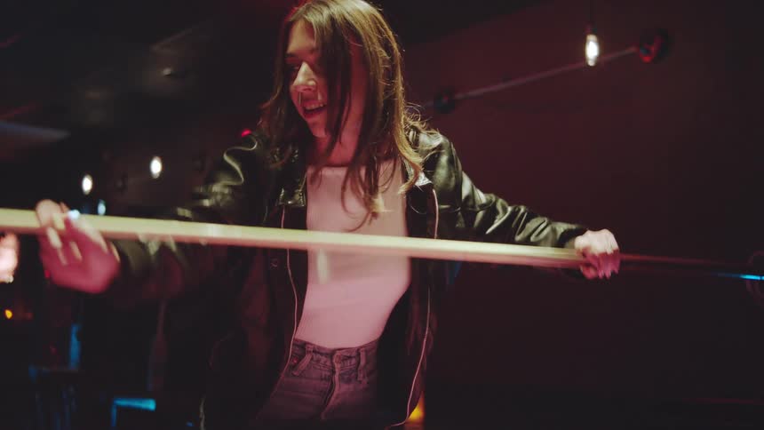 A young couple play a pool game inside a pub at night having fun