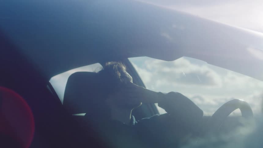 A man hitting a steering wheel while driving