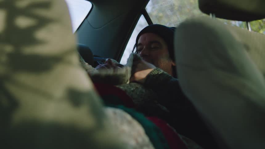 Man sitting in the back seat of a car holding someone resting against his chest