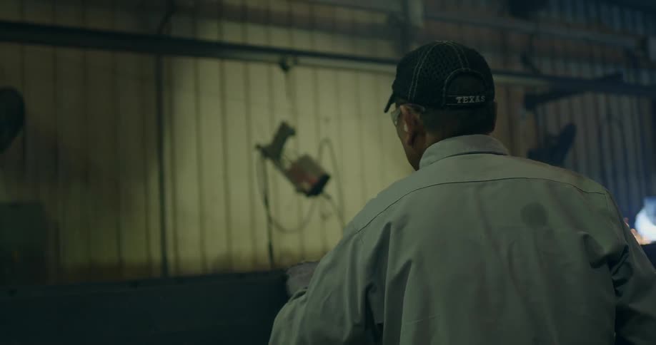A man stands in a shop pulling a beam forward
