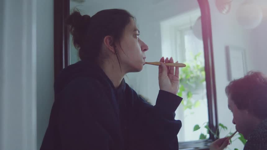 The man and woman brush their teeth in front of a mirror