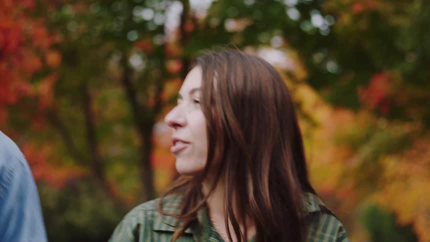 Couple walking in park with orangeleaved trees during autumn