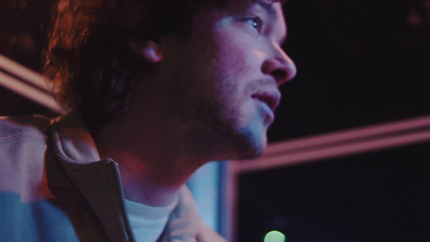 Young adult man looking down and checking something in his hands and then looking around and smiling indoors