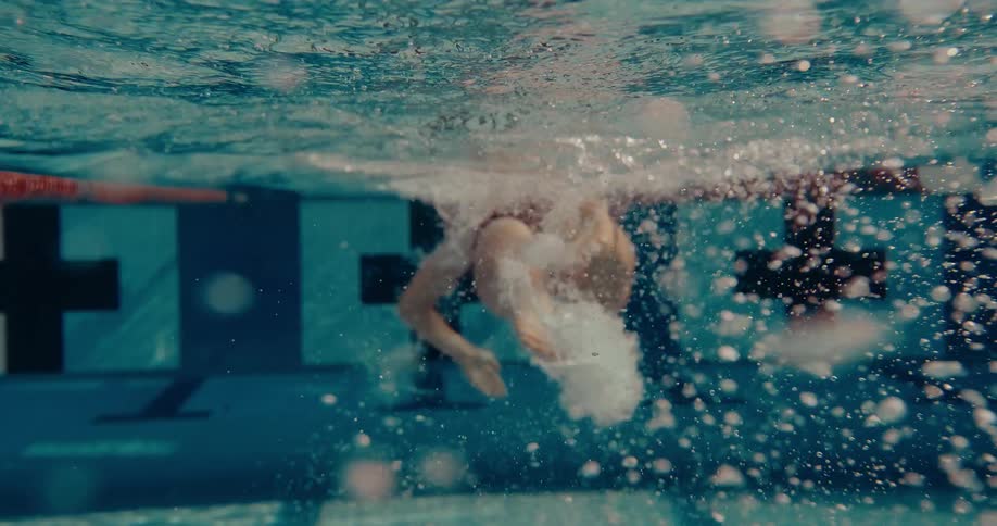 Adult woman wearing a red bathing suit swimming underwater outdoors during day time