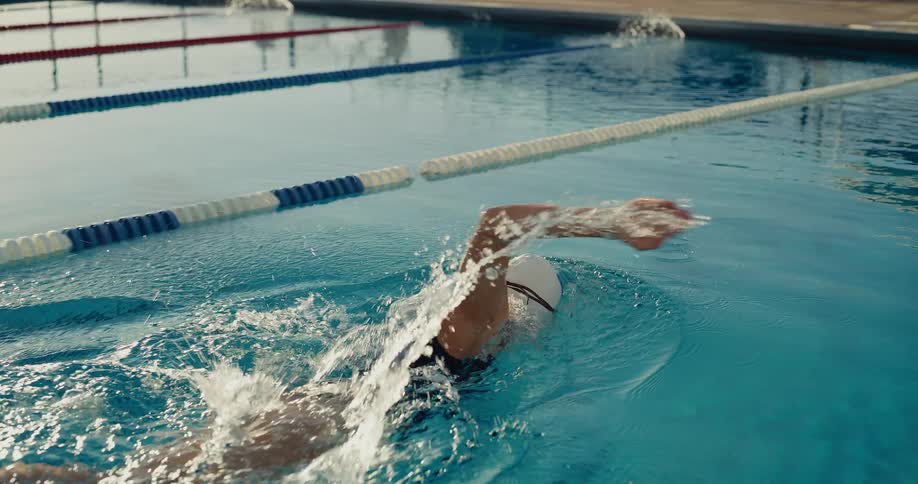 A young woman practices swimming in the pool at midday