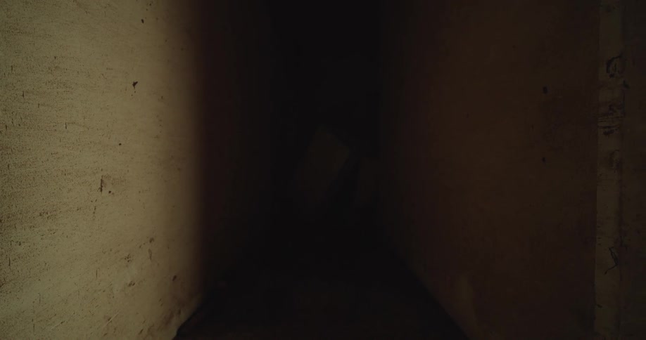 Narrow corridor with concrete walls under low lighting
