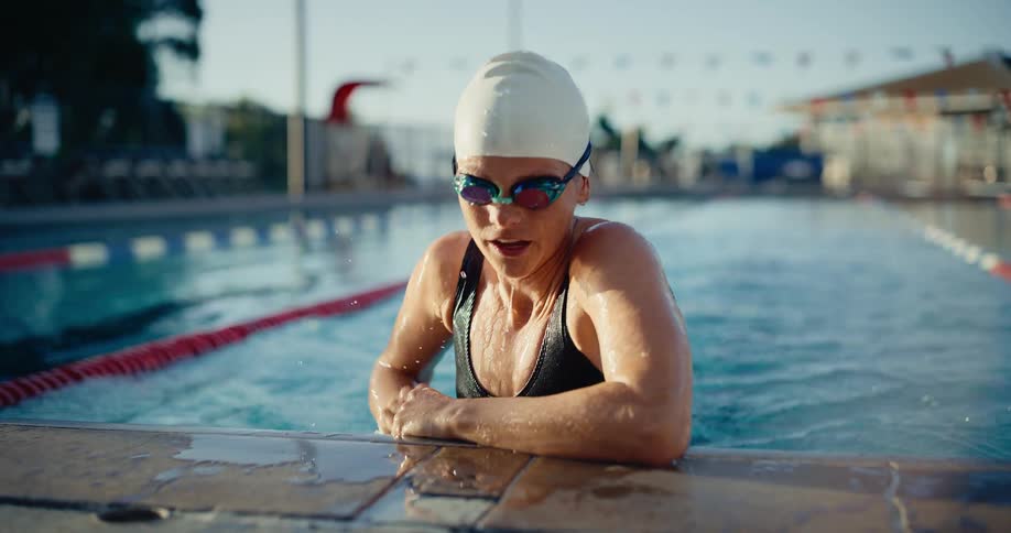 Two clips show a closeup of a person wearing a dark sweater using shears to cut and trim evergreen boughs suggesting a holiday wreath or garlandmaking activitythe third clip features a woman in a white swim cap and goggles completing a lap in an out