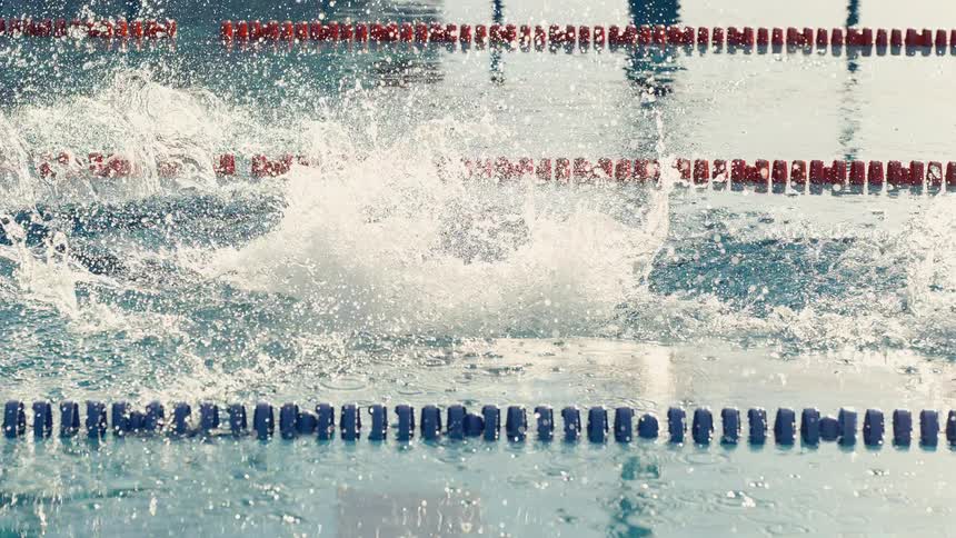 Water splashes as a woman dives into a swimming pool