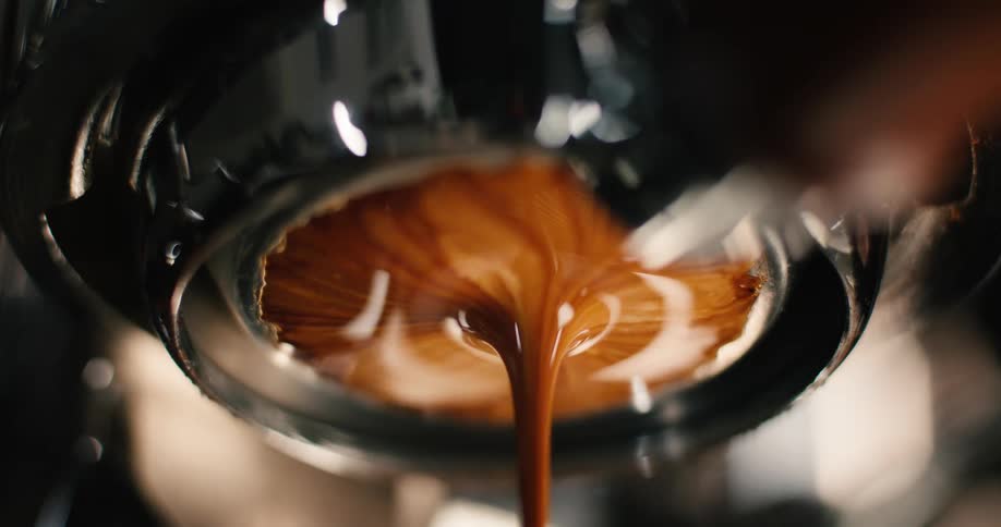 Espresso flowing from portafilter with visible crema layer