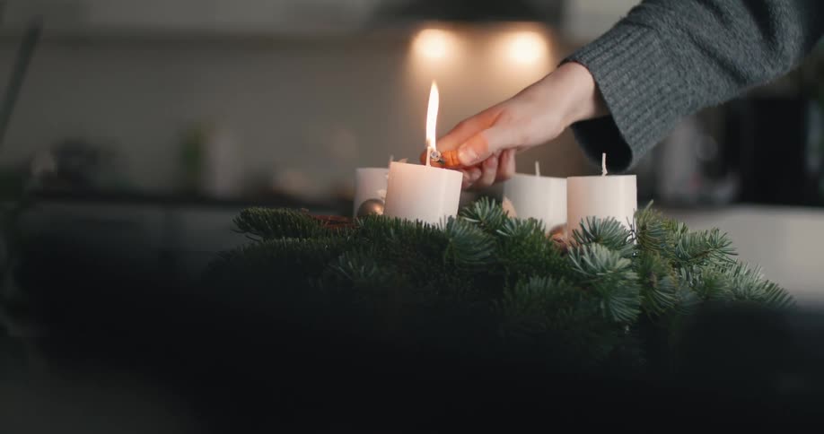 The woman lights candles on a wreath
