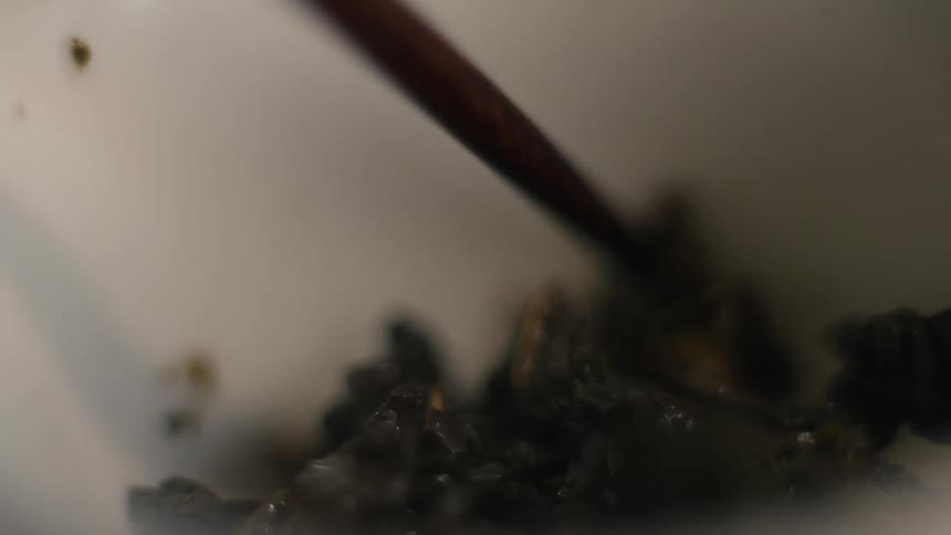 Dark glossy chunks are stirred in bowl with metal utensil in soft culinary scene