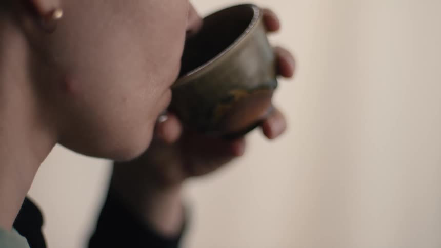 Close up of a woman drinking tea from a teacup indoors during daytime