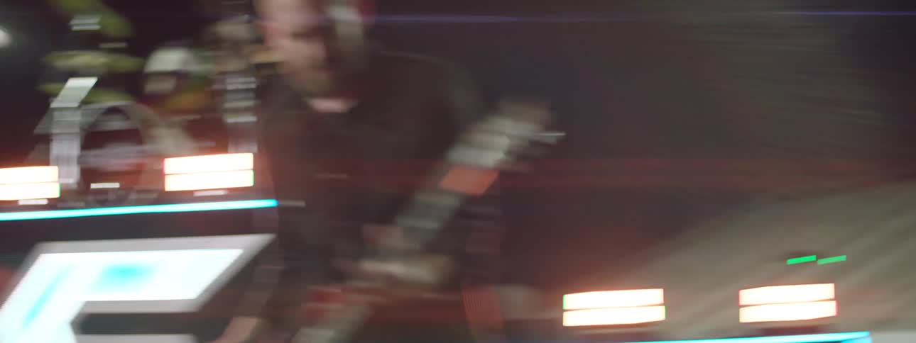 Guitarist performing live with a drummer in the background under stage lighting