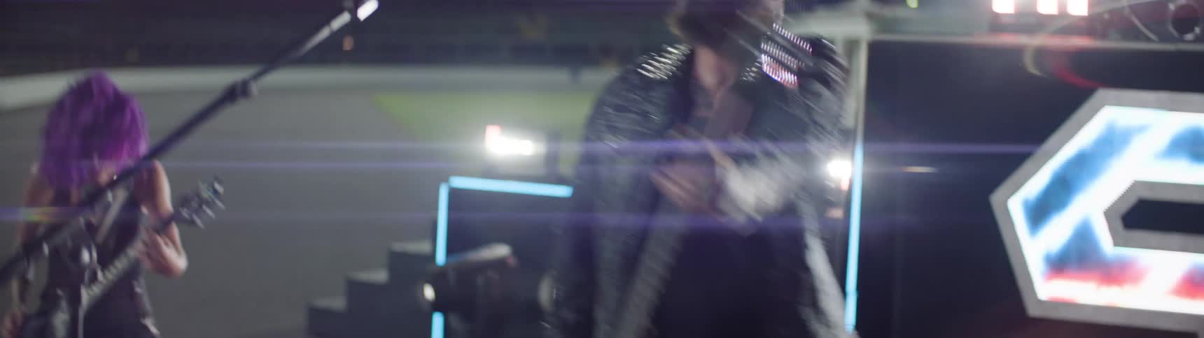 Lead singer plays guitar during the outdoor performance of a band at night