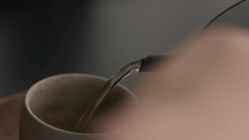Tea being poured into a light ceramic cup