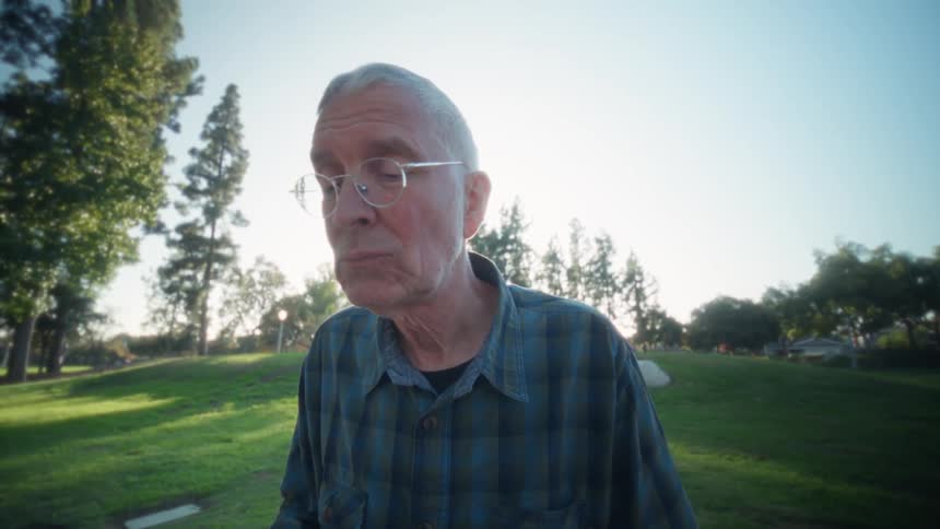 Man sitting outside at a table typing on a laptop computer