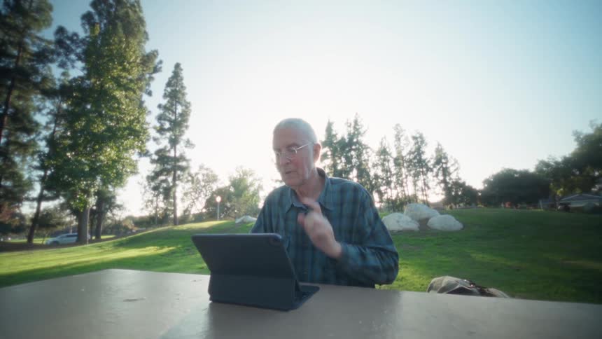Man standing outside at a table with a laptop computer