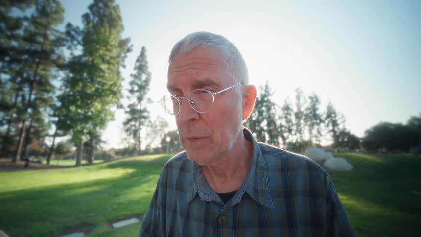 Man sitting outside at a table typing on a laptop computer keyboard