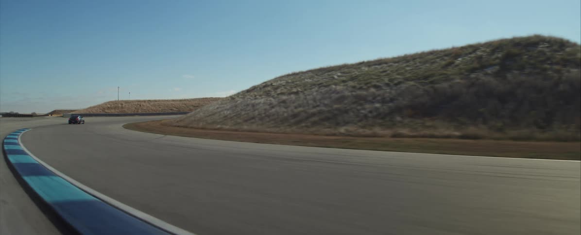 A sports car drives along the freeway at midday making a righthand turn