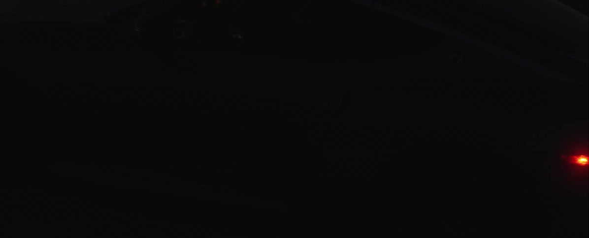 Rear section of silver sports car at high speed with spinning wheel and lights on