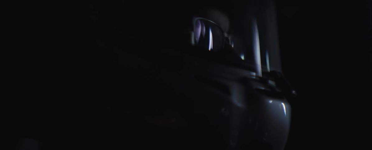 Man wearing glasses and a helmet driving a racing car indoors during night time