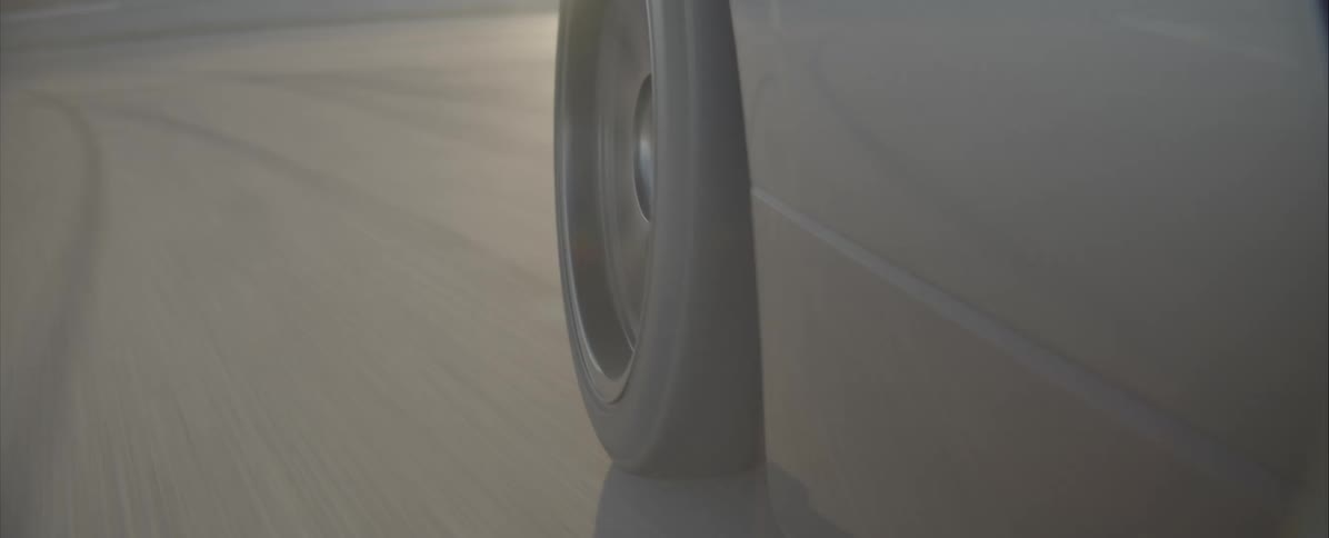 The tire of a car wheel spinning rapidly as the car drives down an asphalt road