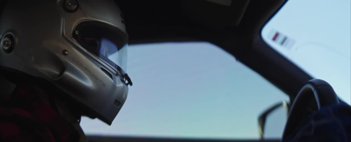 Person wearing a helmet driving a racing car indoors during day time