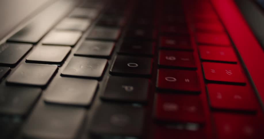 Keyboard on a laptop computer in a room with colorful lights indoors