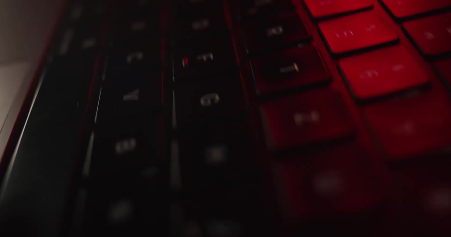 A close up of a laptop keyboard glowing softly under red light