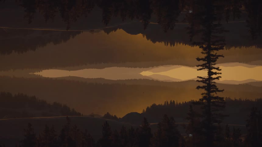 Mountain and tree landscape reflected in a mirrored composition at sunset