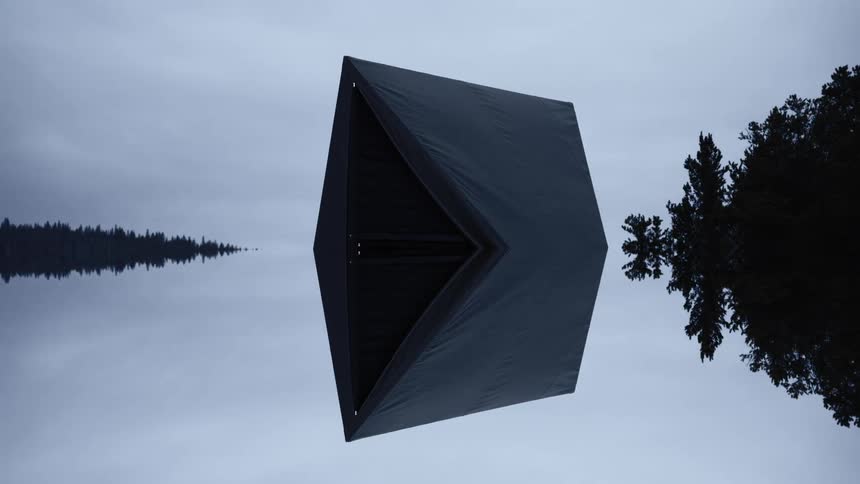 A large black geometric structure appears to float above a reflective lake under a cloudy sky