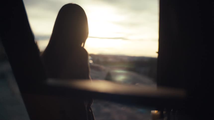 A very close view of a womans brown eye and cheek with wind blowing her dark hair across her face in soft warm light