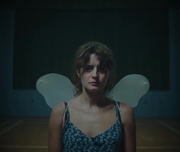 Woman wearing transparent artificial wings in an indoor setting