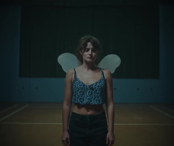 Woman wearing transparent artificial wings standing in an indoor court