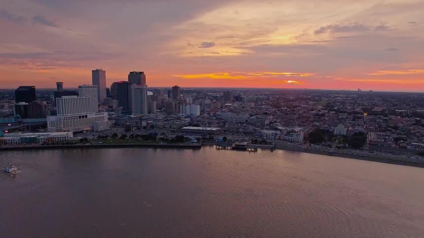Aerial of a city skyline by a river at sunset with glowing reflections