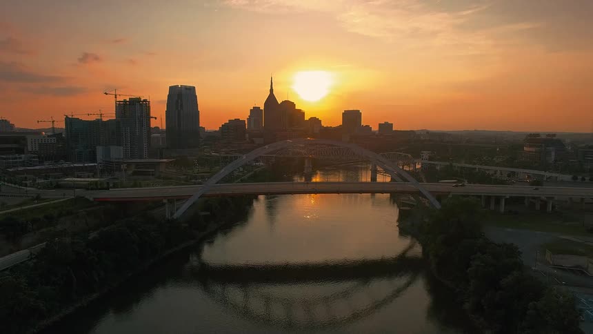 Bridge over a river reflecting the sunset with an urban skyline in the background