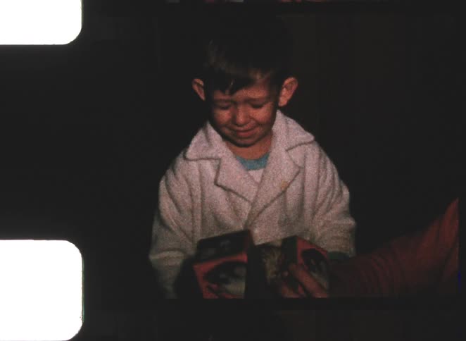 Child in white coat holds gifts and interacts with person