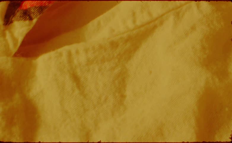 A yellow sweatshirt with a red painting on the front lit clearly by bright sunlight