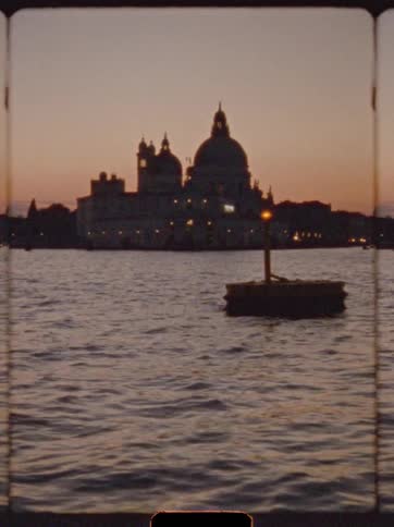 Silhouetted cathedral reflects sunset light over calm waters in nostalgic scene