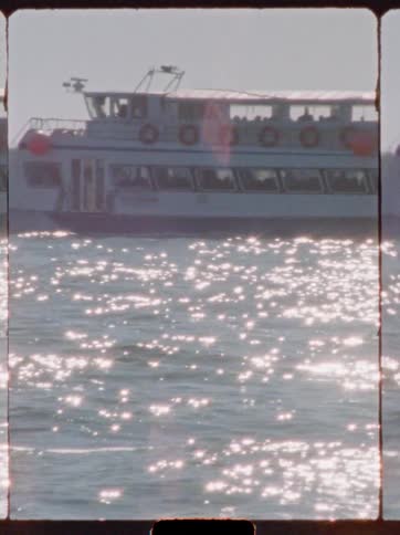 Two ferries pass each other while moving through the reflective water during the day