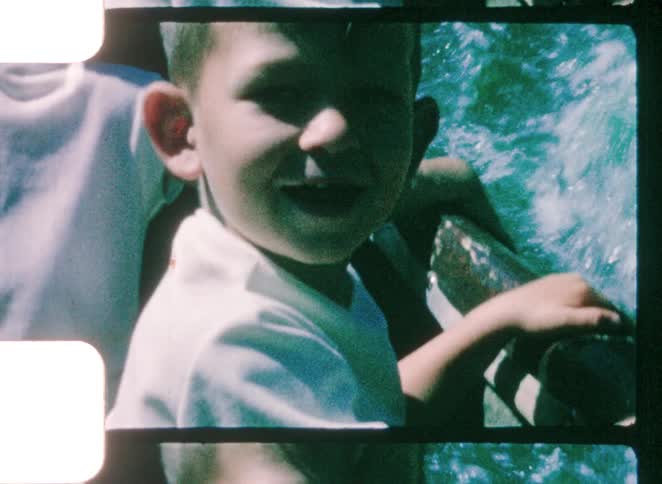 Smiling boy near water while holding onto an edge