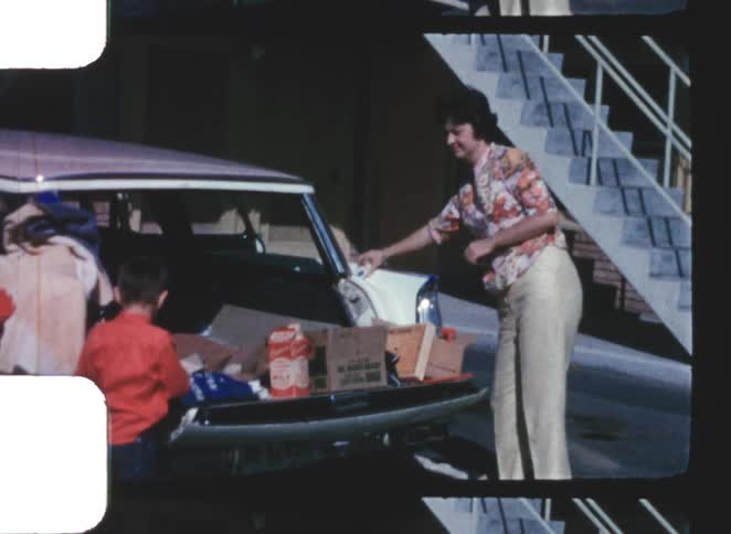 Mother and son organizing items in the trunk of a car