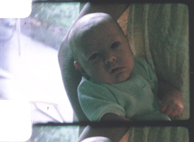 Baby in an adults arms near a window