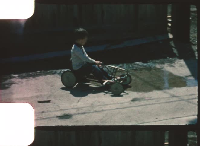 The child rides his kart down the sidewalk