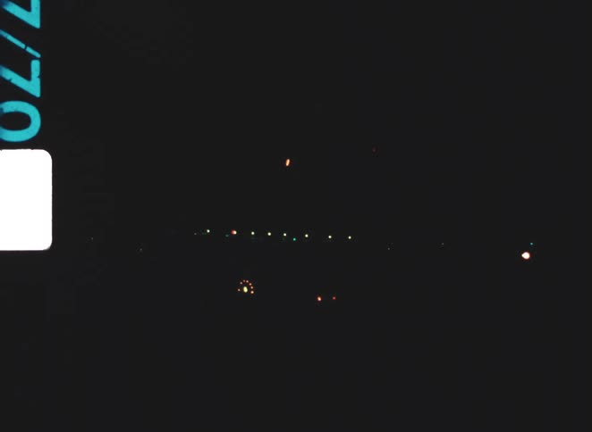 A vintage film shot of a firework show exploding in a dark sky at night