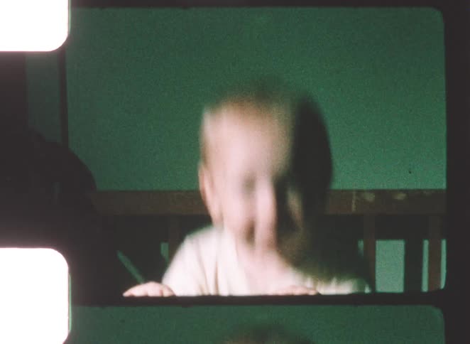 Baby standing inside a crib holding the front rail