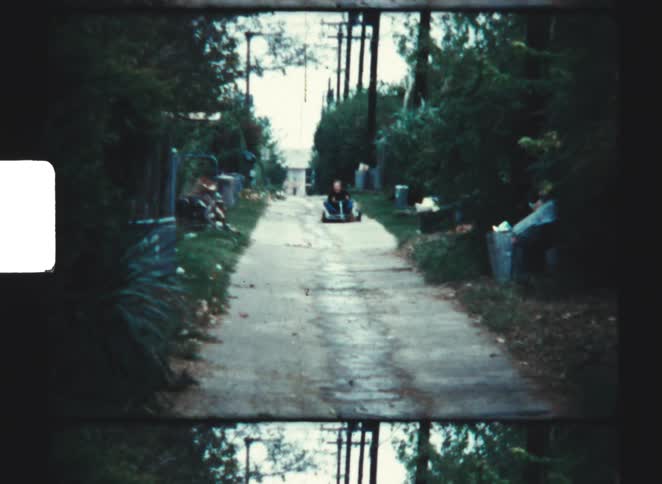 A kid drives a kart down a road