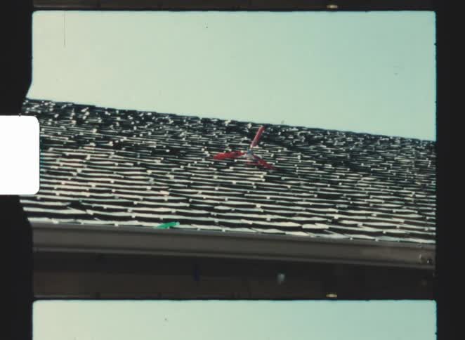 Red toy airplane rests on rooftop under clear sky